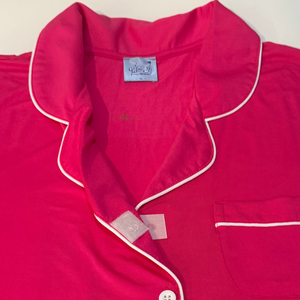 variant:fuchsia A close-up view of the collar of a hot pink adaptive nightgown, showing the fold-down notched collar, the decorative buttons and the Velcro® underneath. The  breast pocket is also visible. The adaptive nightgown is trimmed in white piping.  