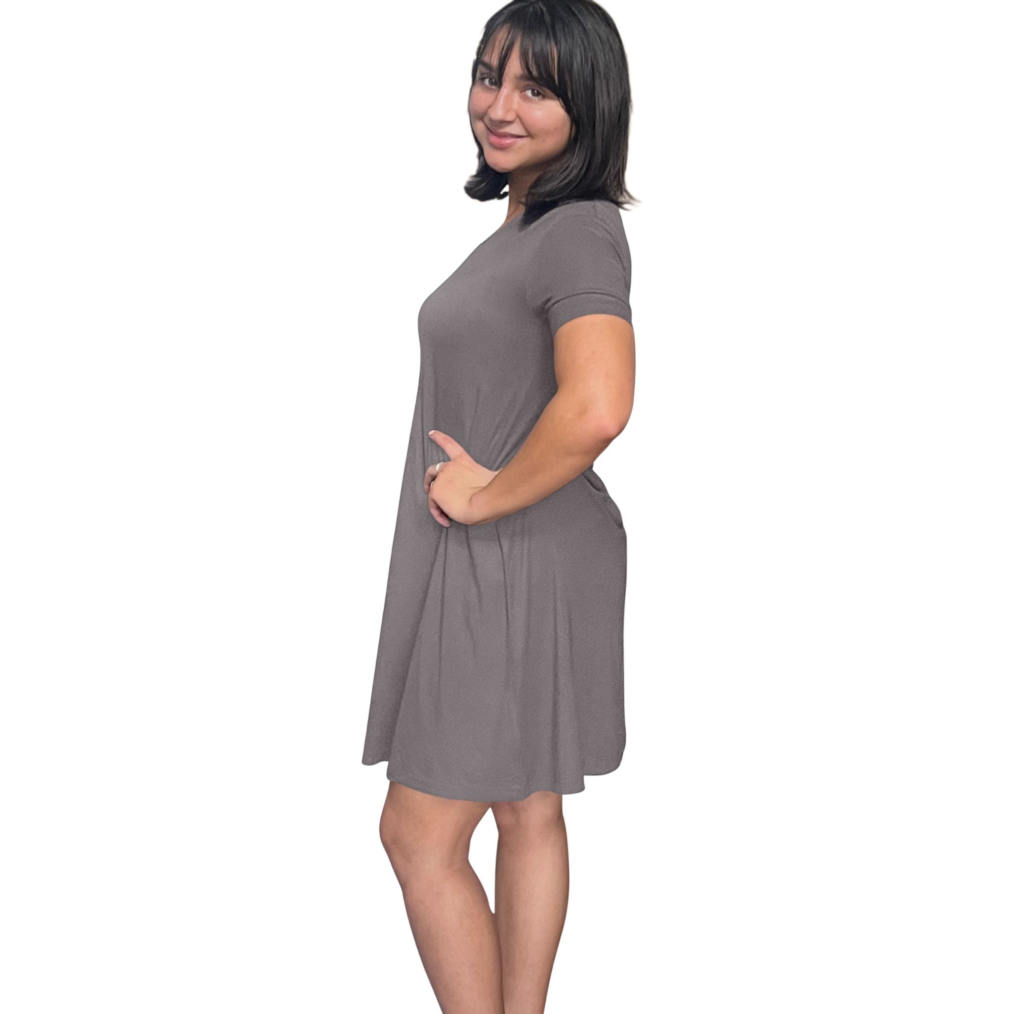 variant::dark-gray A young woman with dark hair wearing a grey v-neck nightshirt with short sleeves that comes just above the knee. It is a side view and and she is looking at the camera. 