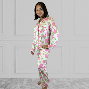 variant::preppy-pickleball A full view of a young woman with dark hair wearing pink and green pickleball printed pajamas with one hand on her hip.  The collar is a fold-down notched collar and the there is a breast pocket. The bamboo long sleeve pajama set is trimmed in pink piping.