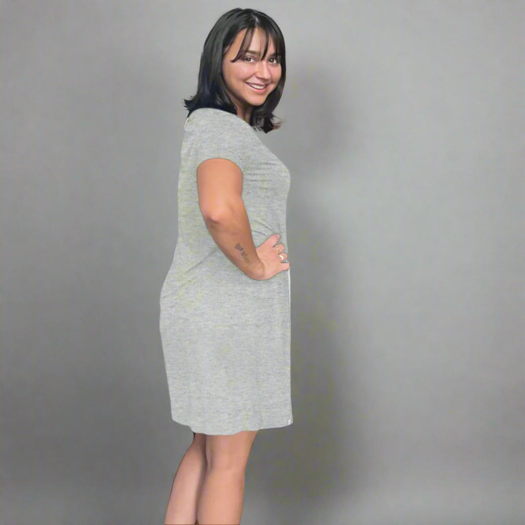 variant::gray A young woman with dark hair wearing a grey v-neck nightshirt with short sleeves that comes just above the knee. She has one hand on her hip. The fabric is Lenzing modal, a cooling fabric that is antibacterial and cooling and made from beech viscose. 