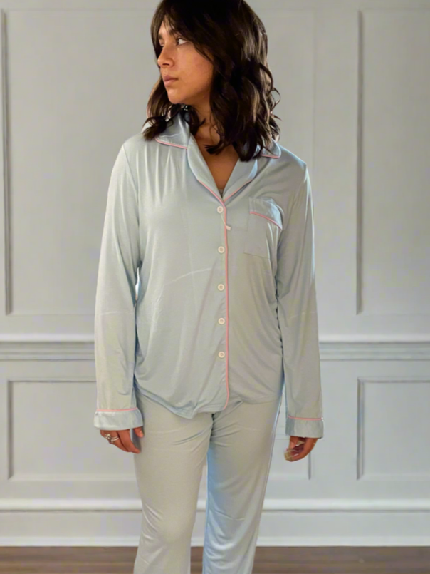variant::baby blue with pink trim  Woman wearing adaptive long sleeve pj set in the baby blue color with piping.  The collar is a fold-down notched collar and the there is a breast pocket.