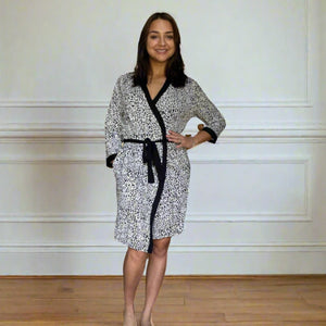 variant::leopard Women's Bamboo Robe modeled by a young woman with shoulder-length brown hair. She is turned to the camera, showcasing the front of the leopard, bamboo robe. The robe is v-neck, has three quarters sleeves, and the robe falls just above her knee.