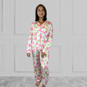 variant::preppy-pickleball A full view of a young woman with dark hair wearing pink and green pickleball printed pajamas with one hand on her hip.  The collar is a fold-down notched collar and the there is a breast pocket. The bamboo long sleeve pajama set is trimmed in pink piping.