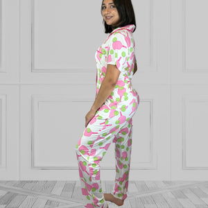 variant::preppy-pickleball Pink and green bamboo pickleball pajama set worn by young woman with dark hair. .background of the pajams is crisp white and the sleeves are short. The pants are cropped jogger style with a tapered leg. 