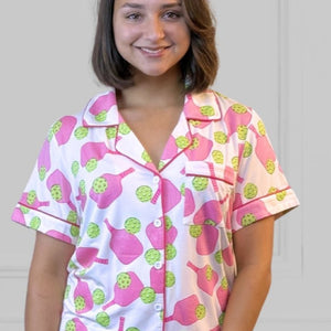 Bamboo Stretch Knit Pickleball print short sleeeve shorty pajama set for pickleball lovers worn by woman with dark brown hair looking forward. The racket is hot pink and the ball is chartreuse. The pajamas are soft, breathable and moisture-wicking. 